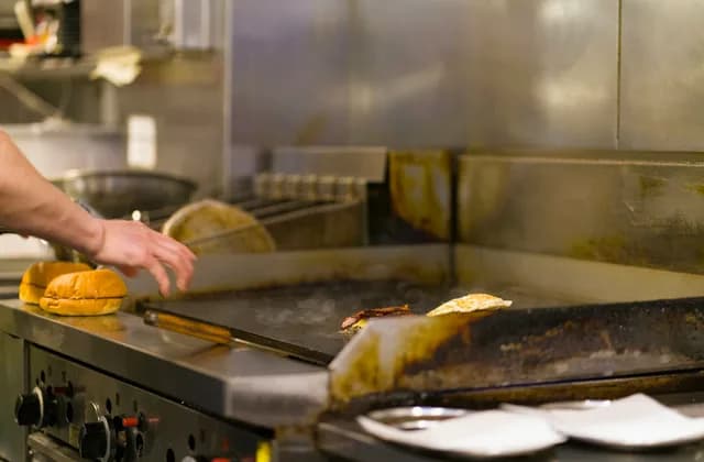 Un cuisinier travaillant à la plancha dans une cuisine professionnelle