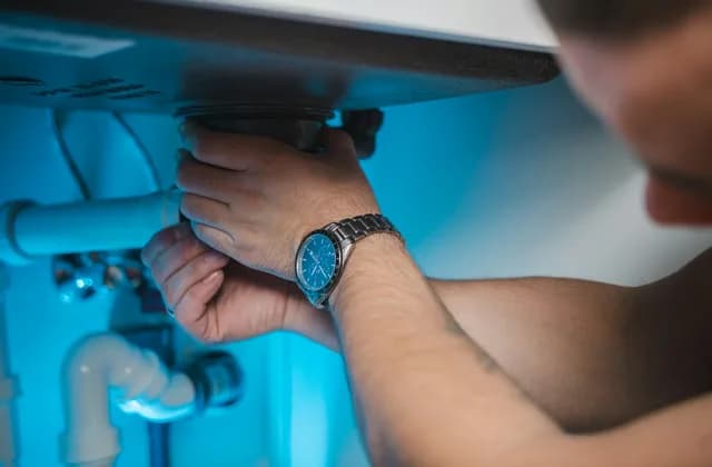 Les mains d’un plombier intervenant sur une installation sanitaire