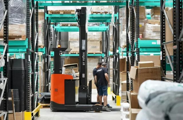 Un chariot à mât rétractable et un magasinier dans une allée de stockage
