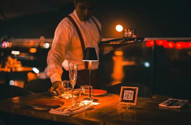 Un serveur dressant une table avec des verres à vin en soirée