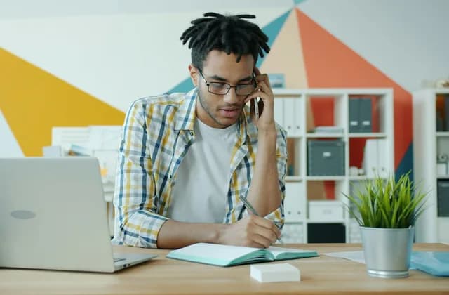 Un recruteur au téléphone prenant des notes à son bureau