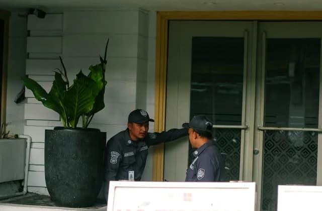 Dois vigilantes uniformizados na entrada de um edifício